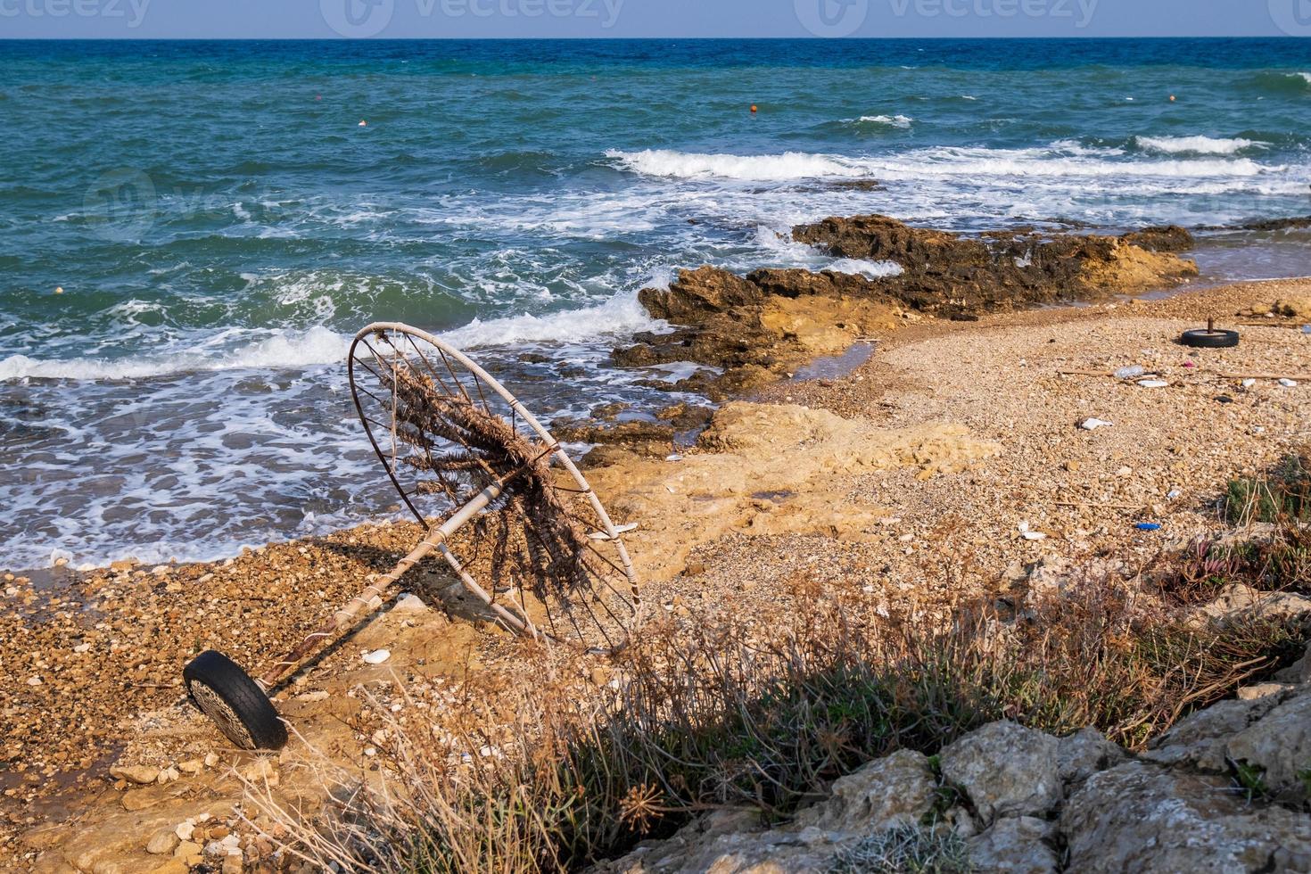 verlaten parasol op een rotsachtig strand tegen de zee foto