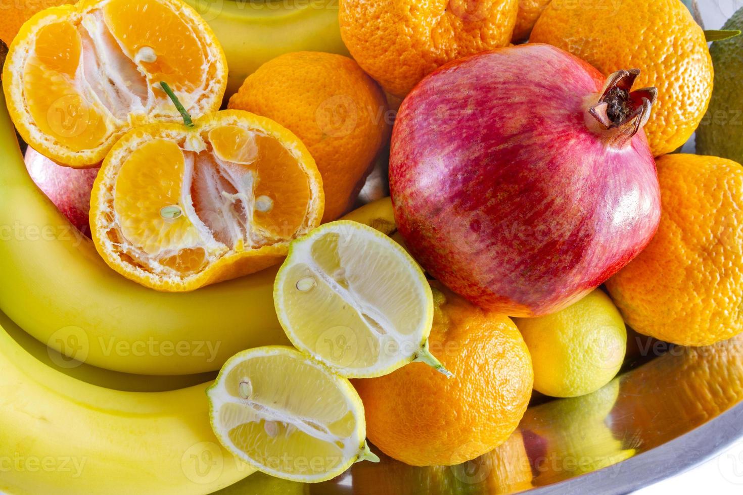 geassorteerde fruit arrangement van bananen, granaatappel, gesneden citroen en gesneden mandarijn foto