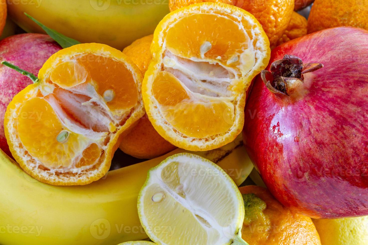 geassorteerde fruit arrangement van bananen, granaatappel, gesneden citroen en gesneden mandarijn foto