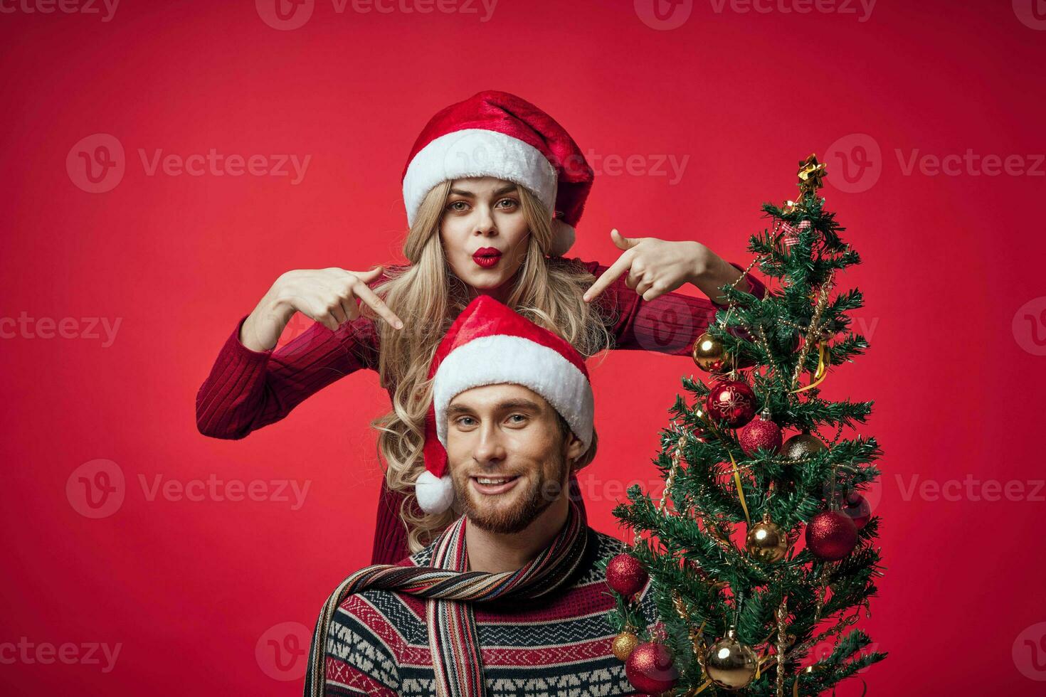 Mens en vrouw Kerstmis boom decoratie pret vakantie rood achtergrond foto