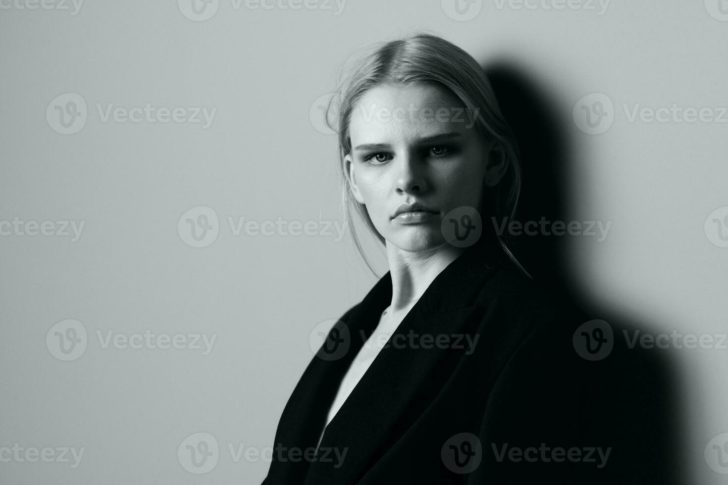 detailopname portret van nadenkend echt blond model- in zwart jasje poseren leunend Aan de studio muur. elegant minimalistisch schieten foto