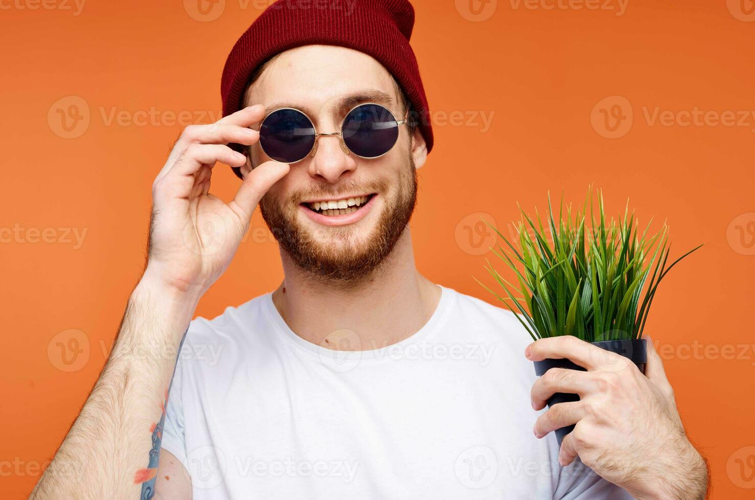 vrolijk Mens in zonnebril Holding een bloem oranje achtergrond foto