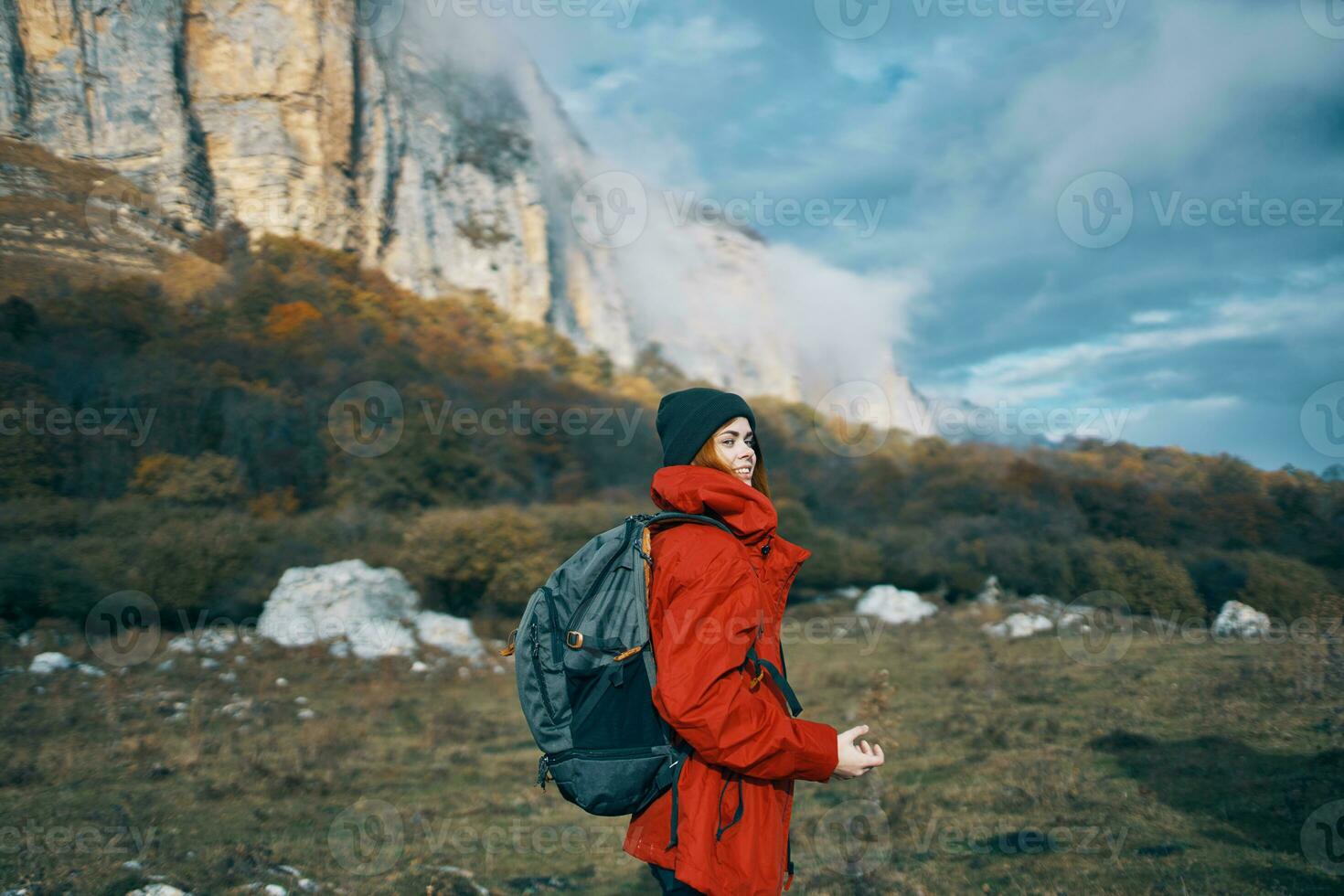 vrouw met rugzak rood jasje naar reizen blauw lucht hoog bergen rotsen landschap foto