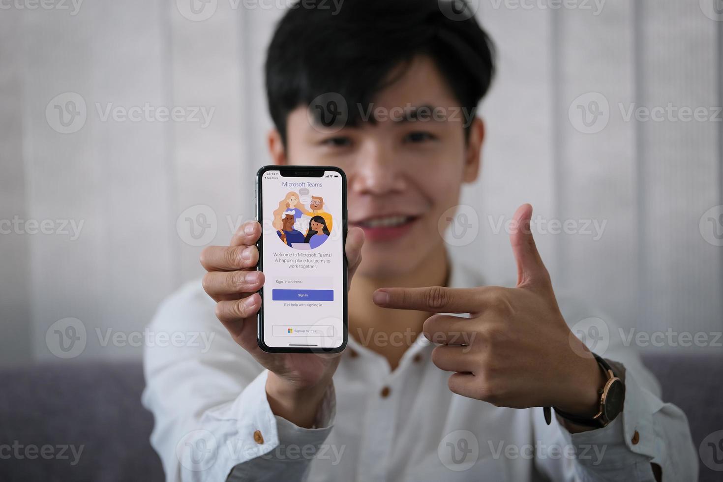 Chiang Mai, Thailand, 23 januari 2021 - Man wijst naar een telefoon met Microsoft Teams erop foto