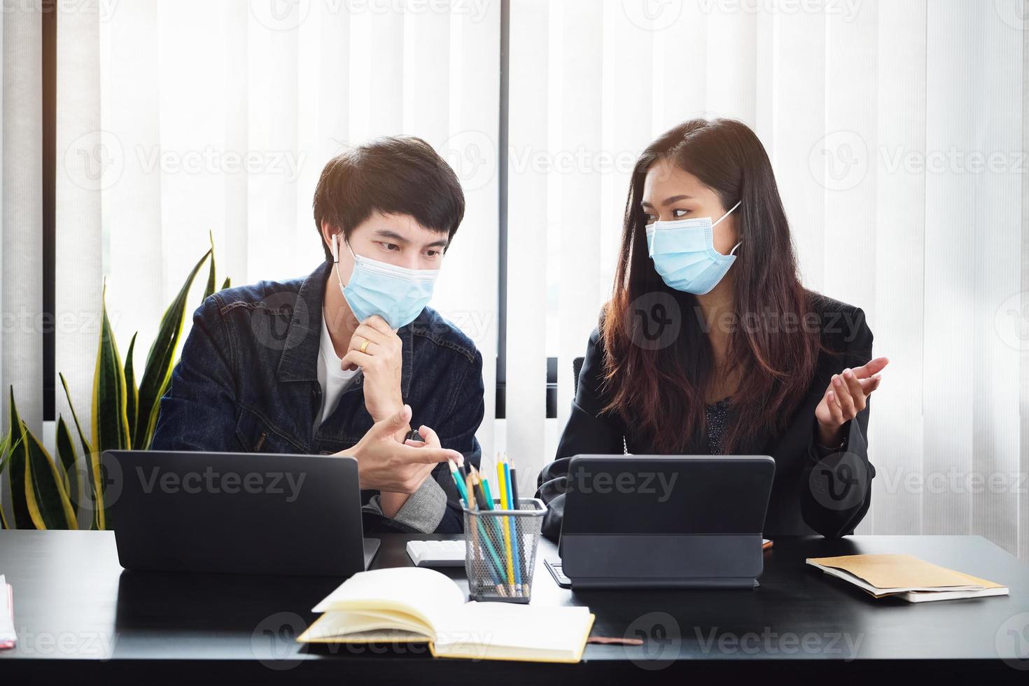 twee jonge bedrijfsleiders in een vergadering met maskers op foto