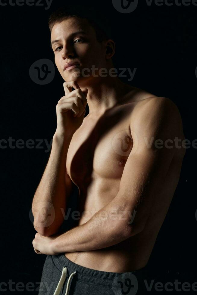 atleet houdt zijn hand- in de buurt de gezicht bodybuilder geschiktheid donker achtergrond portret foto
