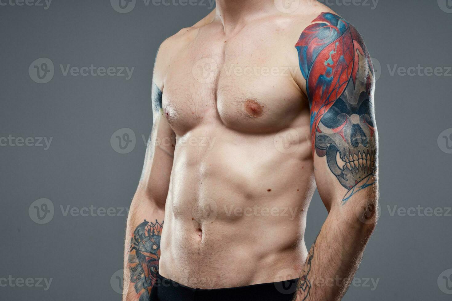 sportief Mens met gemotiveerd omhoog buikspieren tatoeages Aan zijn armen grijs achtergrond spieren foto