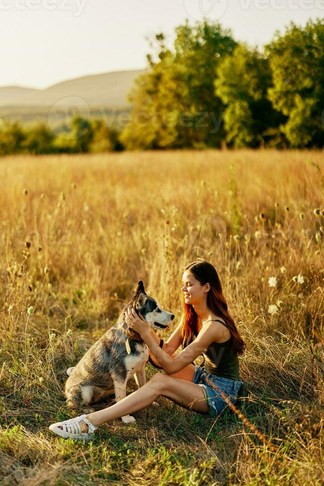 vrouw zittend in veld- met teckel hond glimlachen terwijl uitgeven tijd in natuur met vriend hond in herfst Bij zonsondergang terwijl op reis foto