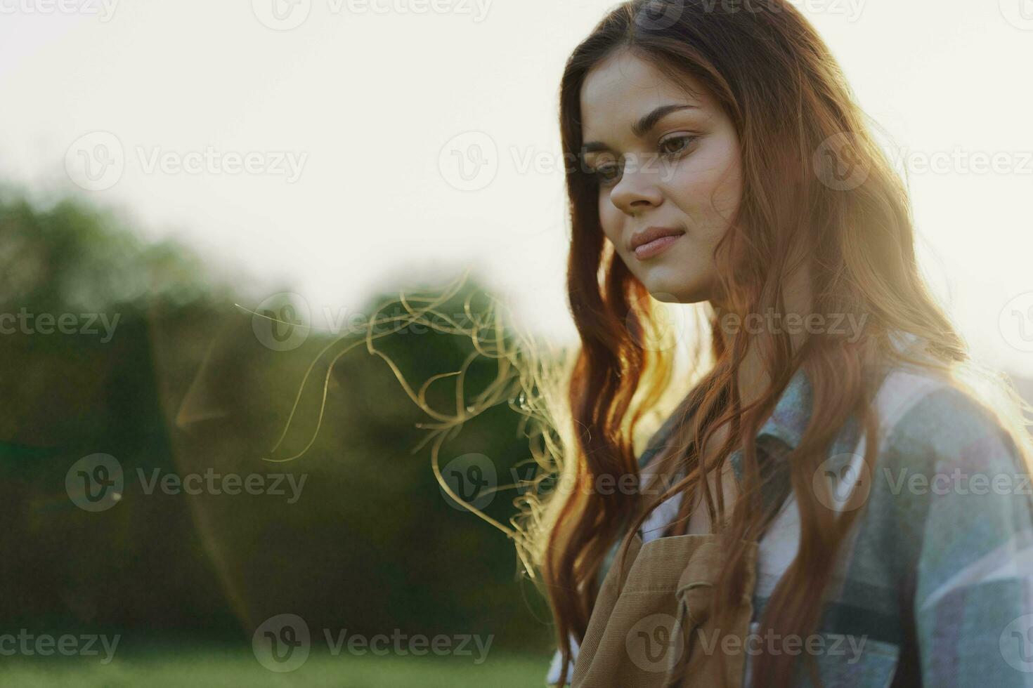 portret van een vrouw met een mooi glimlach en Rechtdoor tanden Aan een zomer dag in de zonsondergang met vliegend gekruld haar- foto