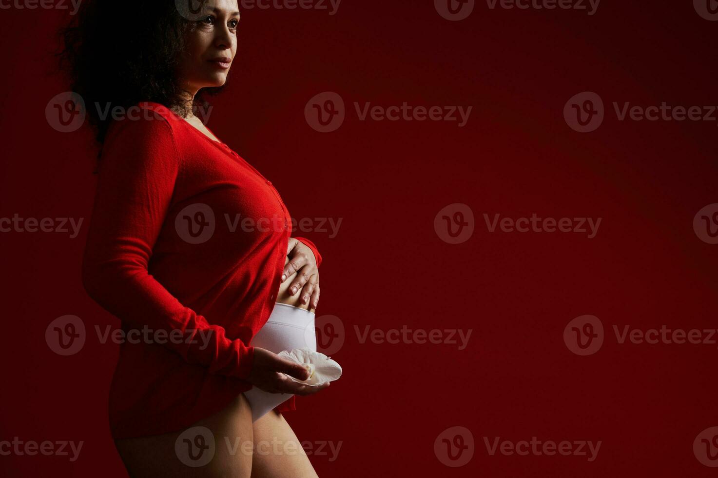 sereen volwassen zwanger vrouw Holding haar hand- Aan haar buik, geïsoleerd Aan rood achtergrond. vrouwen dag. gelukkig moeder dag foto