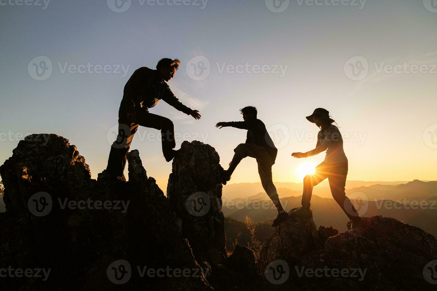 silhouet van wandelaars beklimming omhoog berg klif. concept van helpen en teamwerk, beklimming groep helpen elk andere terwijl beklimming omhoog in zonsondergang. limieten van leven en wandelen succes vol. foto