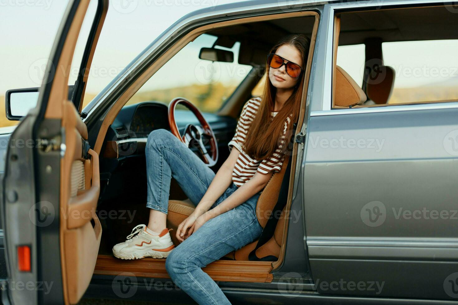 een vrouw bestuurder in zonnebril gestopt de auto Aan de weg in een pktkshestvie en is resting op zoek Bij een mooi visie foto