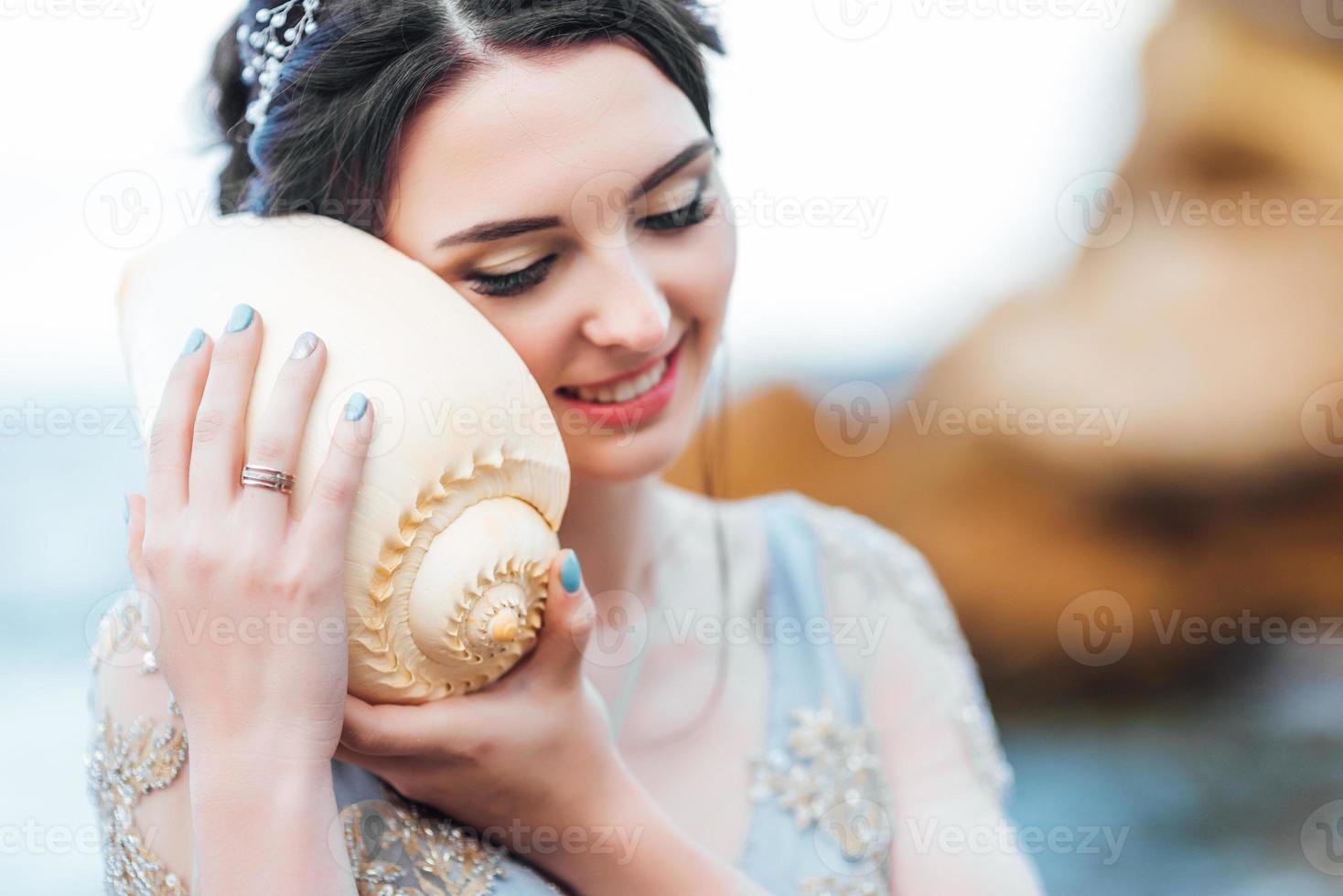 bruid met een grote schelp op het strand foto