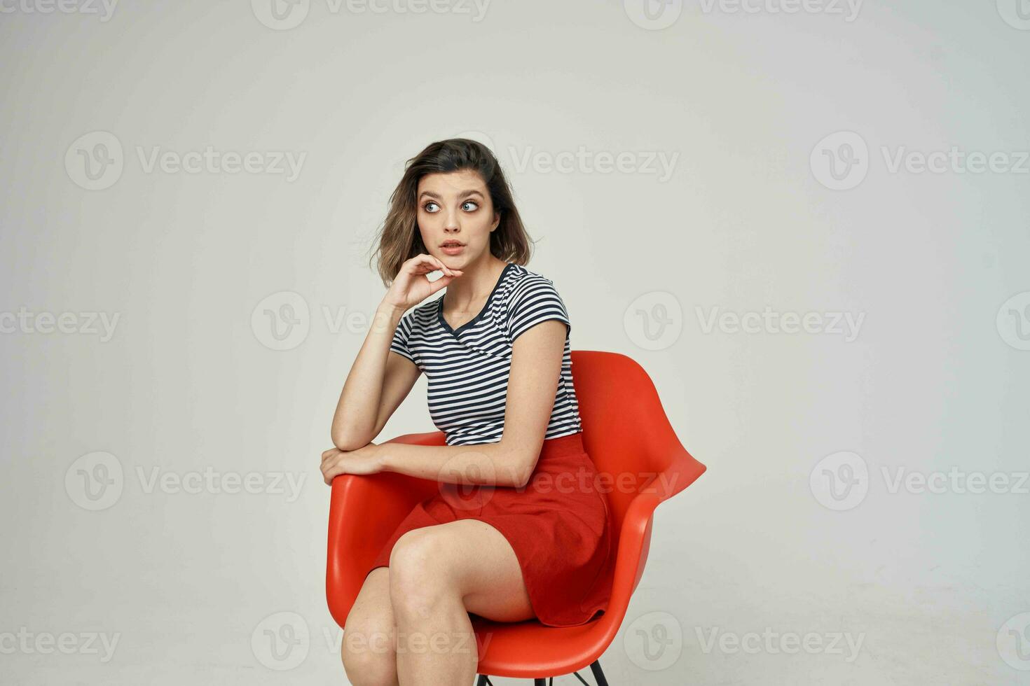 mooi vrouw met bril zittend Aan de rood stoel poseren studio foto