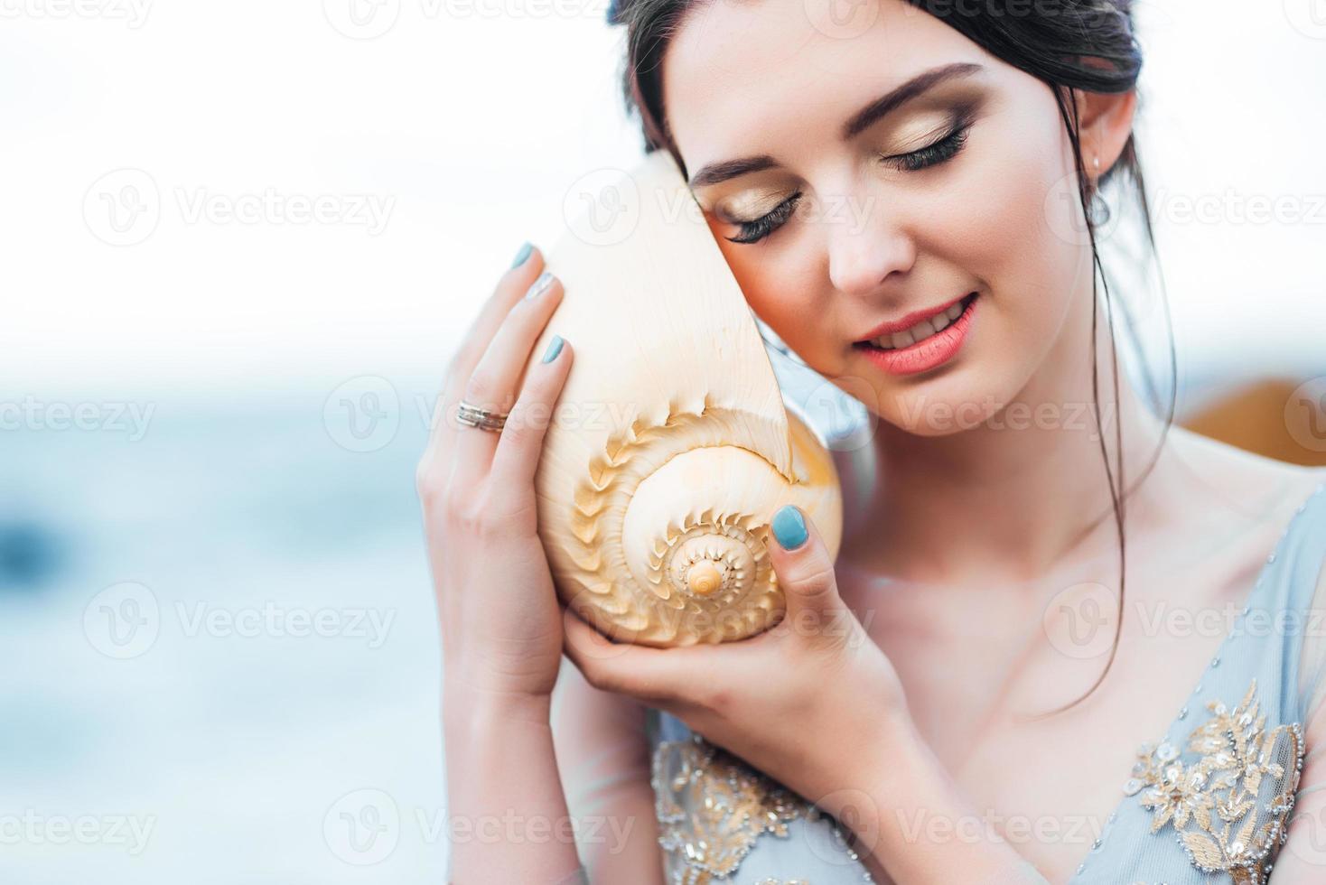 bruid met een grote schelp op het strand foto