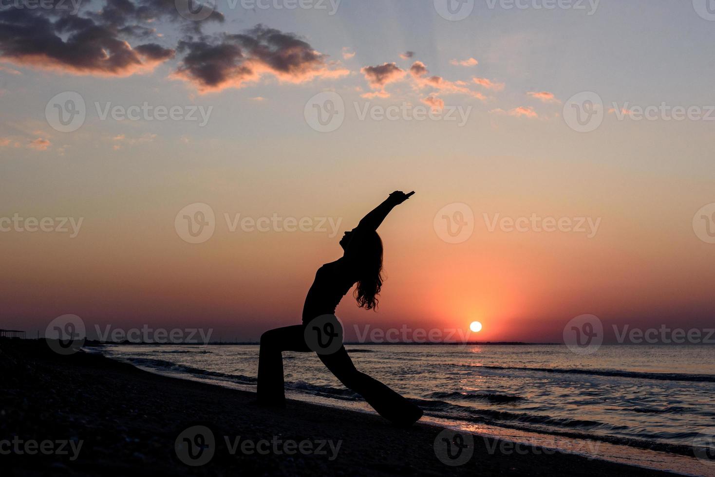 meisje op het strand bij dageraad in yoga assana foto