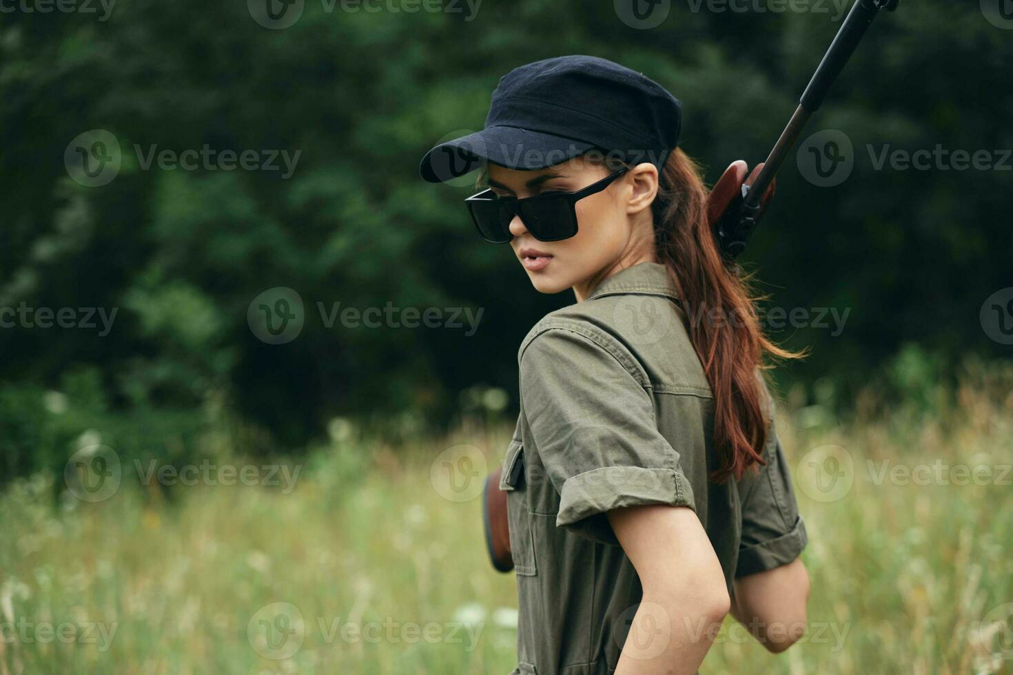 vrouw zonnebril jachtgeweer groen jumpsuit vers lucht foto