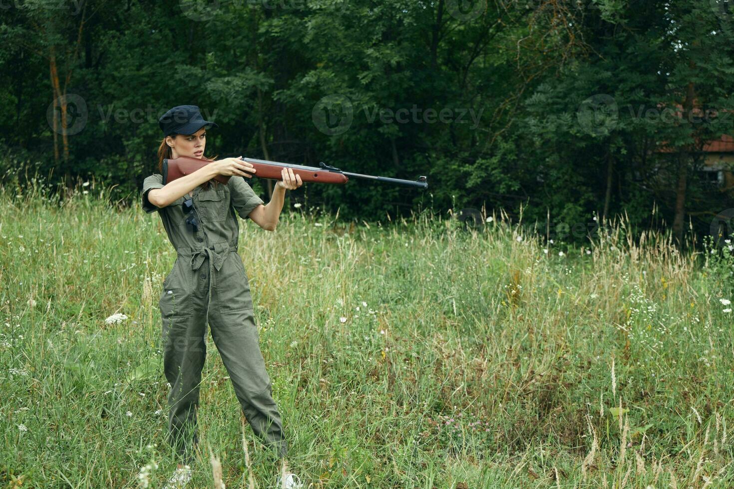 vrouw soldaat hij is Holding een geweer in een groen jacht- overall vers lucht foto