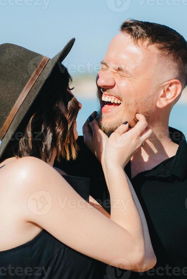 jong stel een man met een meisje in zwarte kleren lopen op het witte zand foto