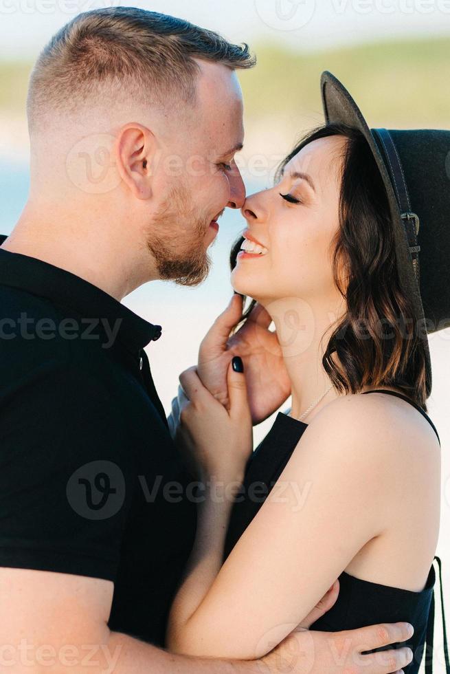 jong stel een man met een meisje in zwarte kleren lopen op het witte zand foto