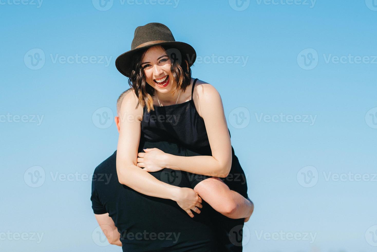 jong stel een man met een meisje in zwarte kleren lopen op het witte zand foto