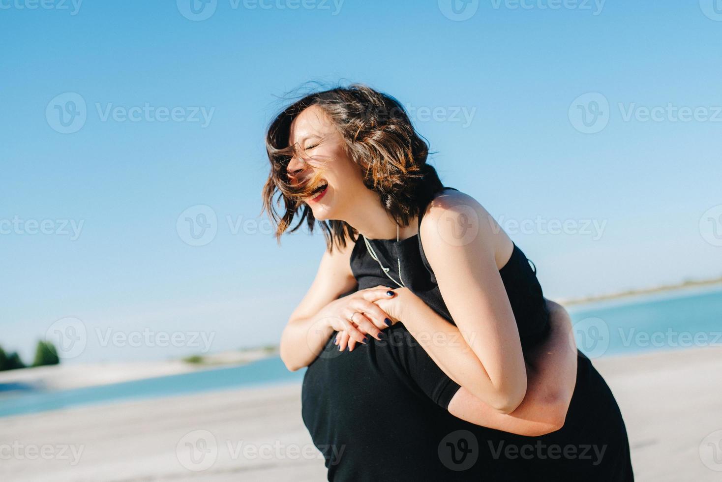 jong stel een man met een meisje in zwarte kleren lopen op het witte zand foto