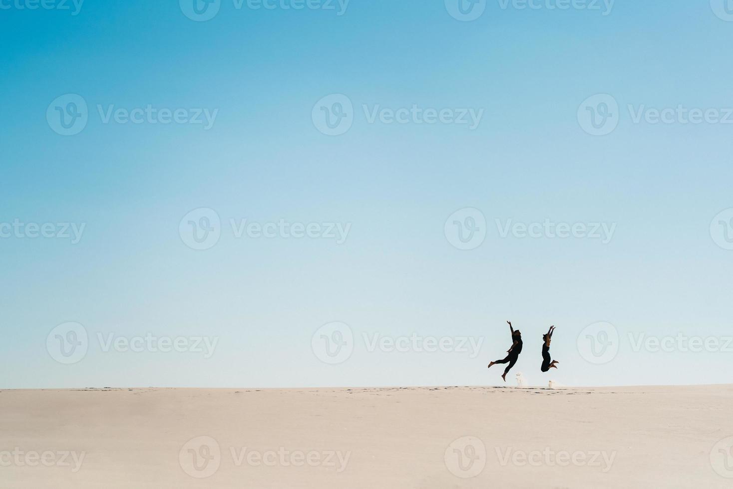jong koppel een jongen en een meisje met vrolijke emoties in zwarte kleding lopen door de witte woestijn foto