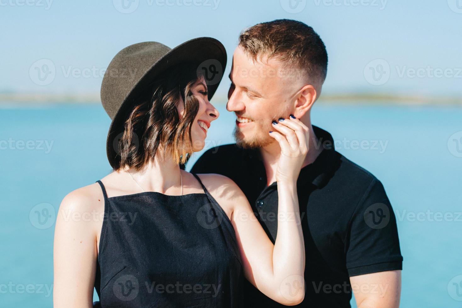 jong stel een man met een meisje in zwarte kleren lopen op het witte zand foto