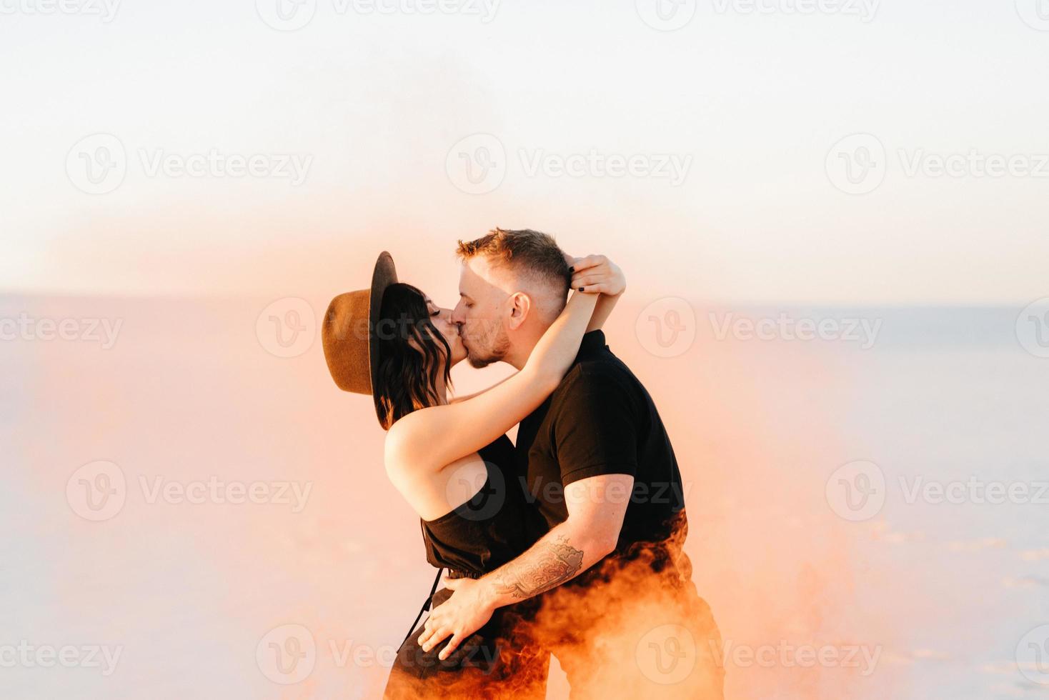 jongen en een meisje in zwarte kleren knuffelen en rennen op het witte zand foto