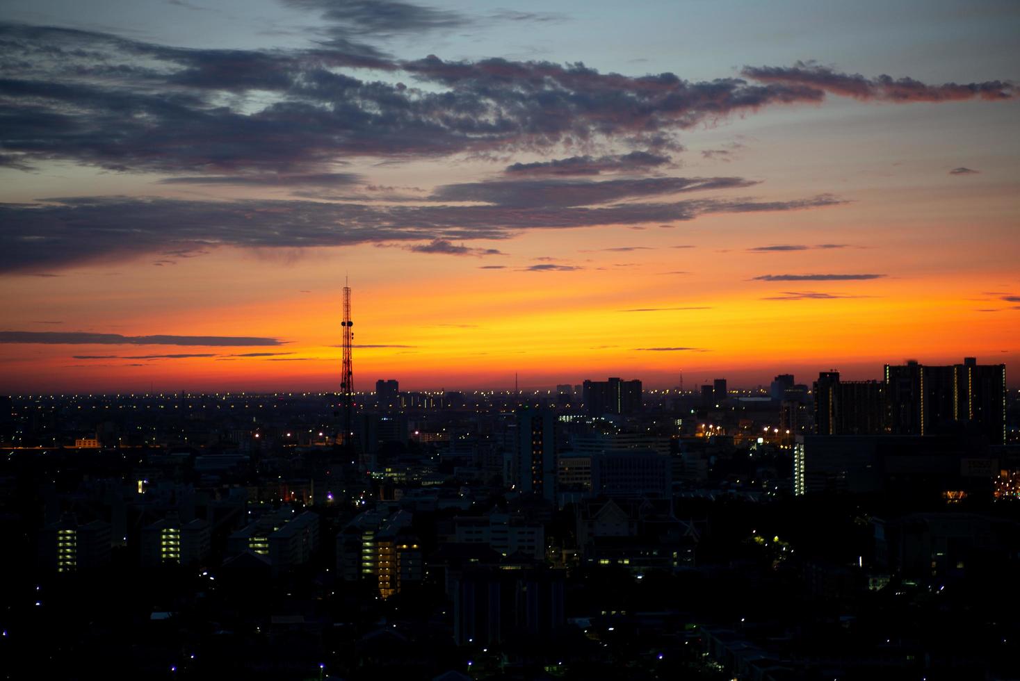 silhouet van antennetoren in de stad met licht van een zonsopgang en een bewolkte hemel op de achtergrond foto