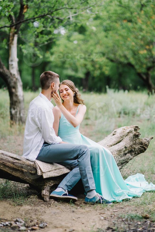 gelukkige man in een wit overhemd en een meisje in een turquoise jurk lopen in het bospark foto