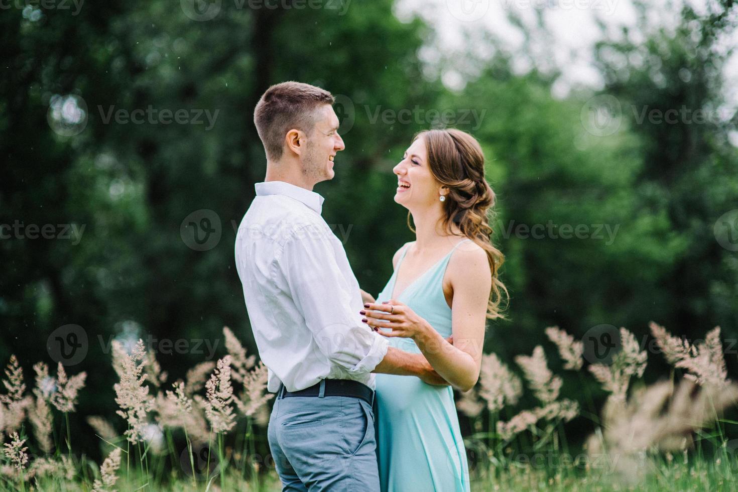 gelukkige man in een wit overhemd en een meisje in een turquoise jurk lopen in het bospark foto