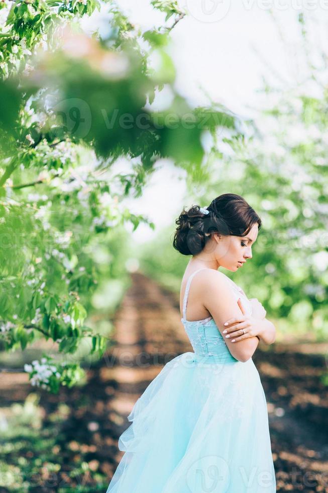 brunette meisje in een turquoise jurk in de lentetuin foto