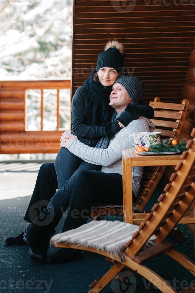 paar jonge mensen een jongen en een meisje op de veranda van een besneeuwd houten huis foto