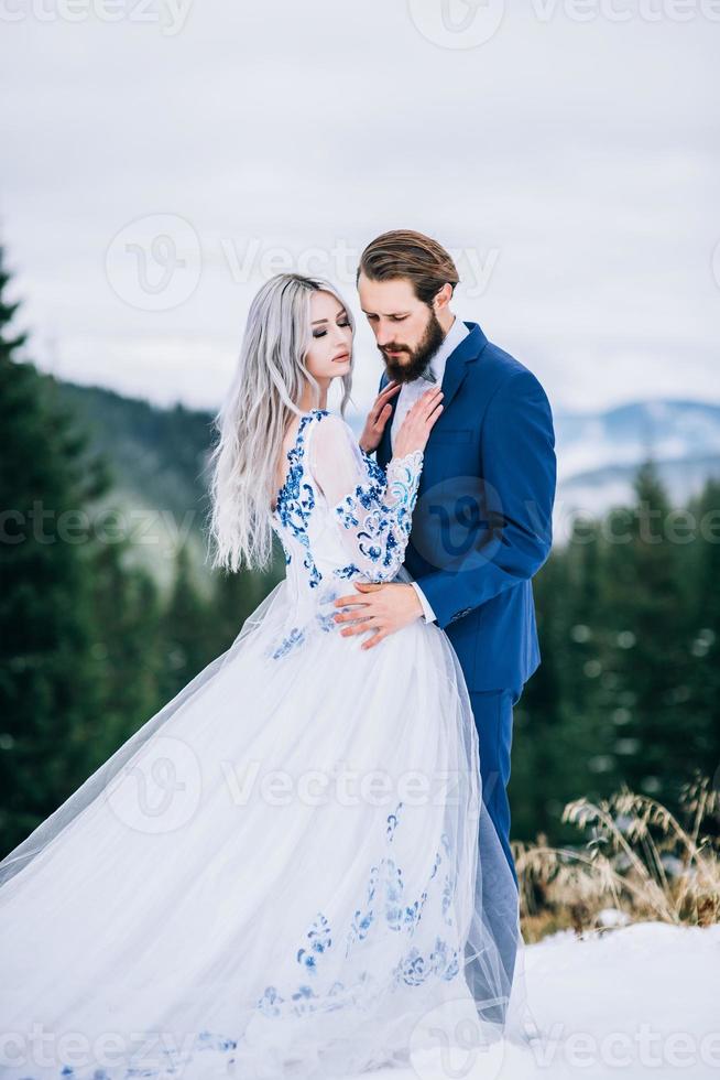 bruidegom in een blauw pak en bruid in het wit in de bergen van de Karpaten foto