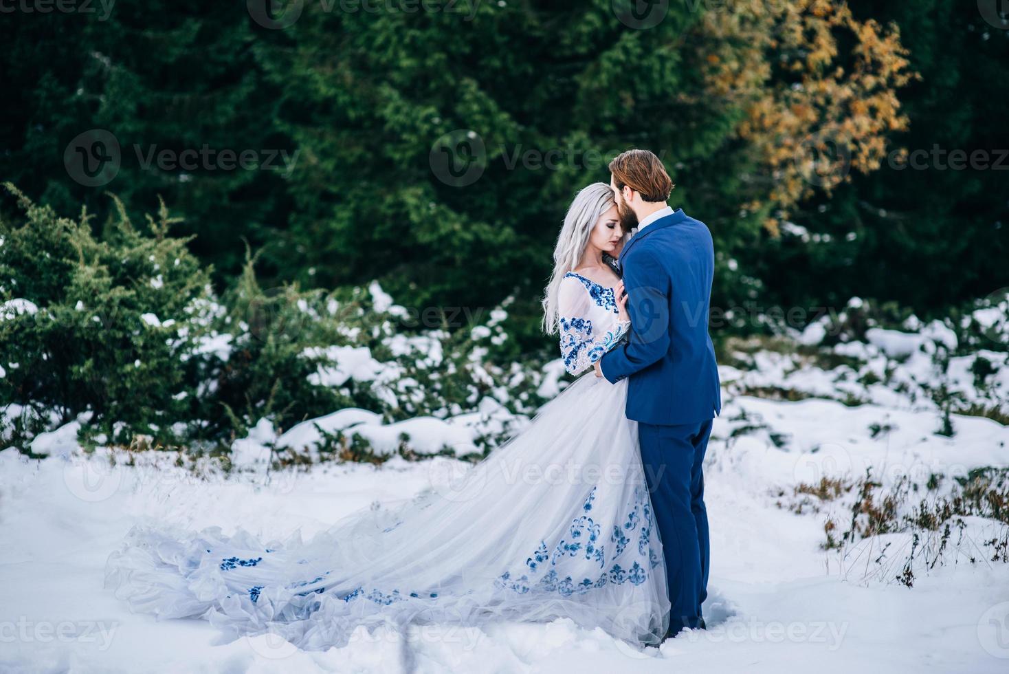 bruidegom in een blauw pak en bruid in het wit in de bergen van de Karpaten foto