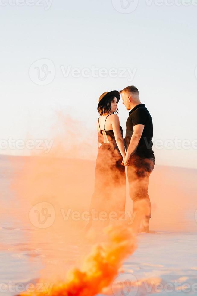 jongen en een meisje in zwarte kleren knuffelen en rennen op het witte zand foto