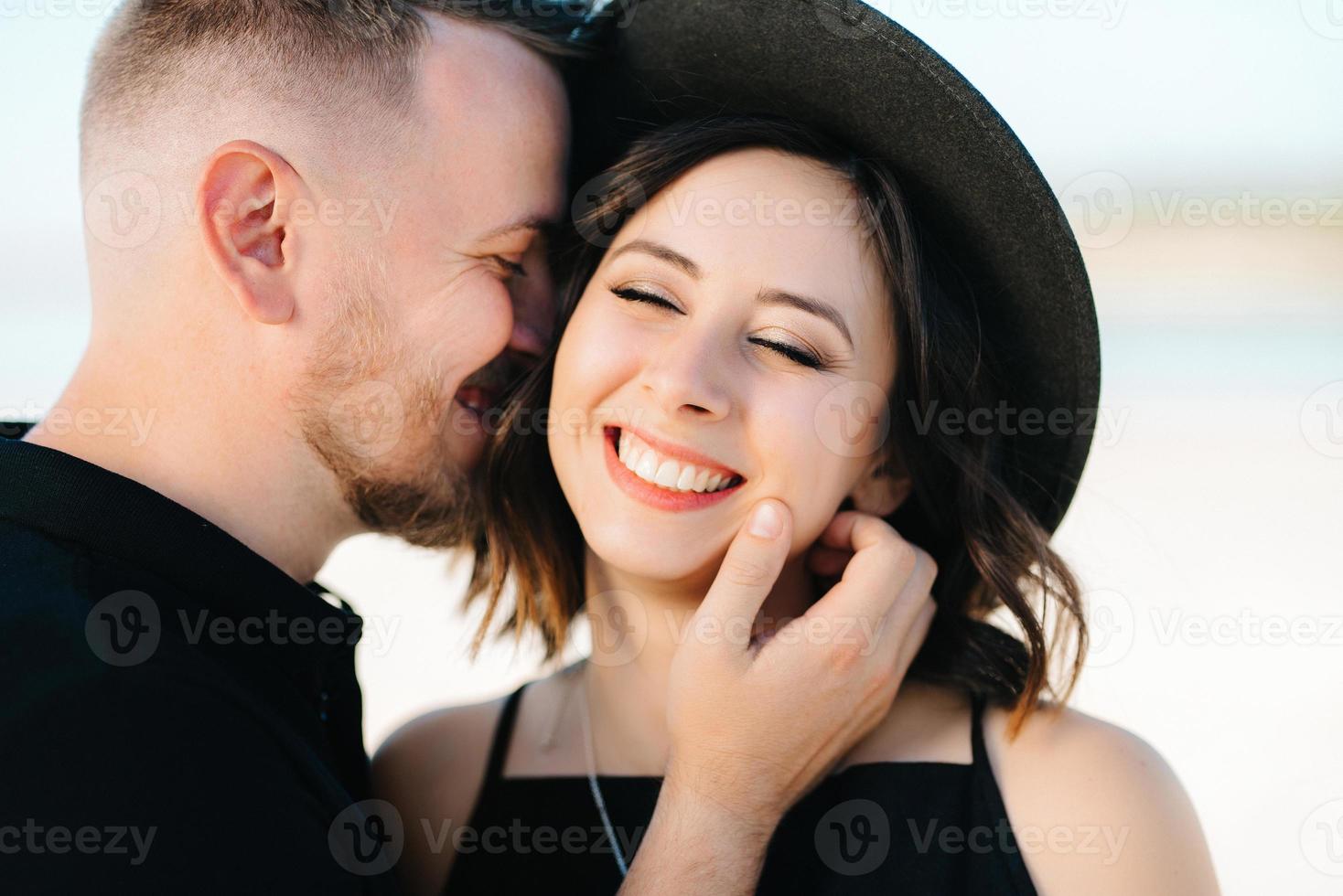 jong koppel een jongen en een meisje met vrolijke emoties in zwarte kleding lopen door de witte woestijn foto