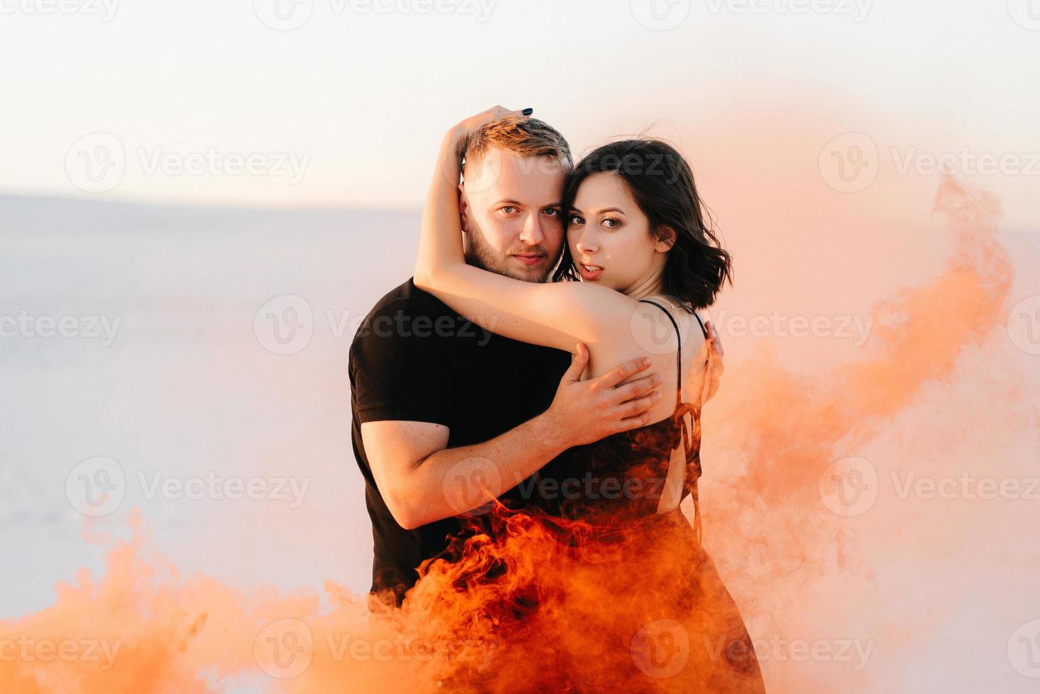 jongen en een meisje in zwarte kleren knuffelen en rennen op het witte zand foto