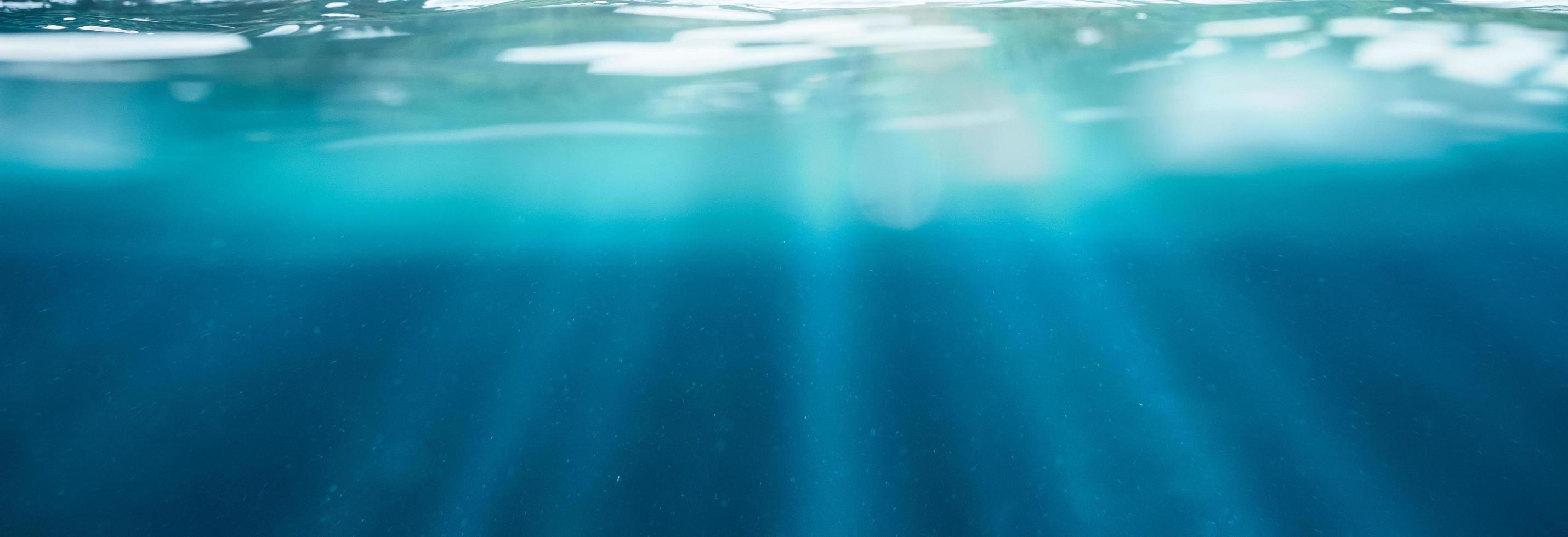 blauwe onderwater met zonlicht schijnt door het wateroppervlak in tropische zee foto