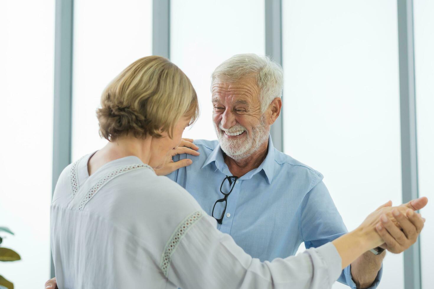 gelukkig senior paar familie, romantisch blanken volwassen, volwassen minnaar, gepensioneerd echtgenoot, vrouw hebben plezier, genieten van terwijl uitgeven tijd dansen samen in leven kamer Bij huis. glimlachen ouderen Mens, vrouw. foto