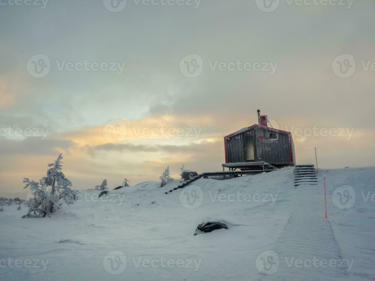 knus noordelijk gast huis Aan een besneeuwd heuvel Bij ochtendgloren. cabine in winter ochtendgloren. eenzaam huis Aan een heuveltop in de koel ochtend. foto