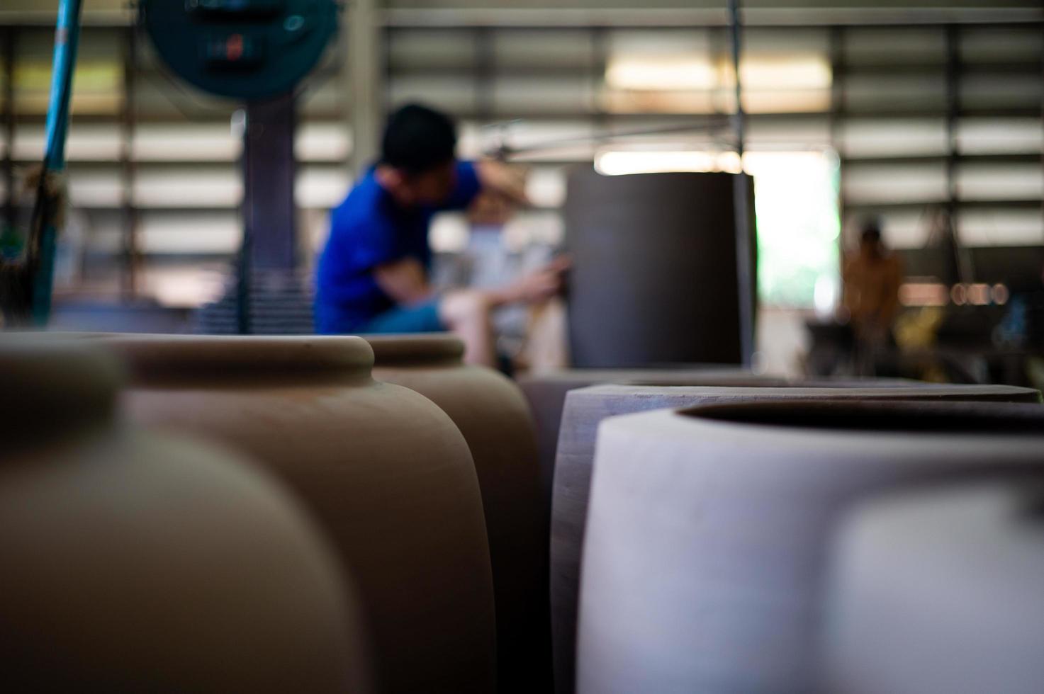 close-up foto van traditionele klei aardewerk in de fabriek met wazig werknemer werkt op de achtergrond