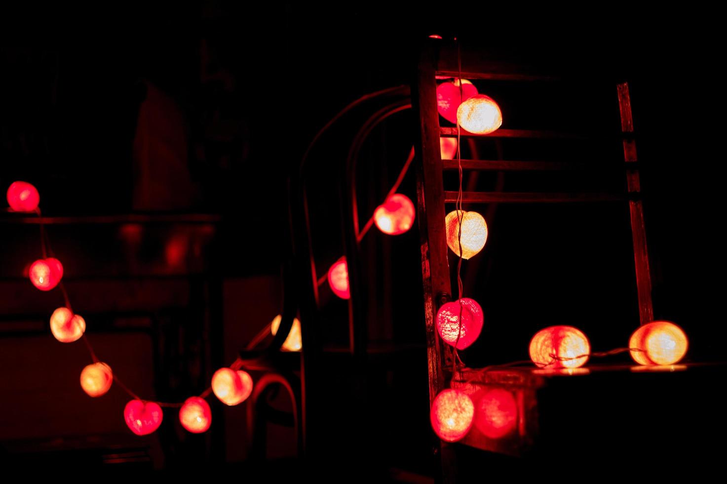 close-up hartvormige led-verlichting opknoping op houten stoelen ingericht in de donkere kamer foto