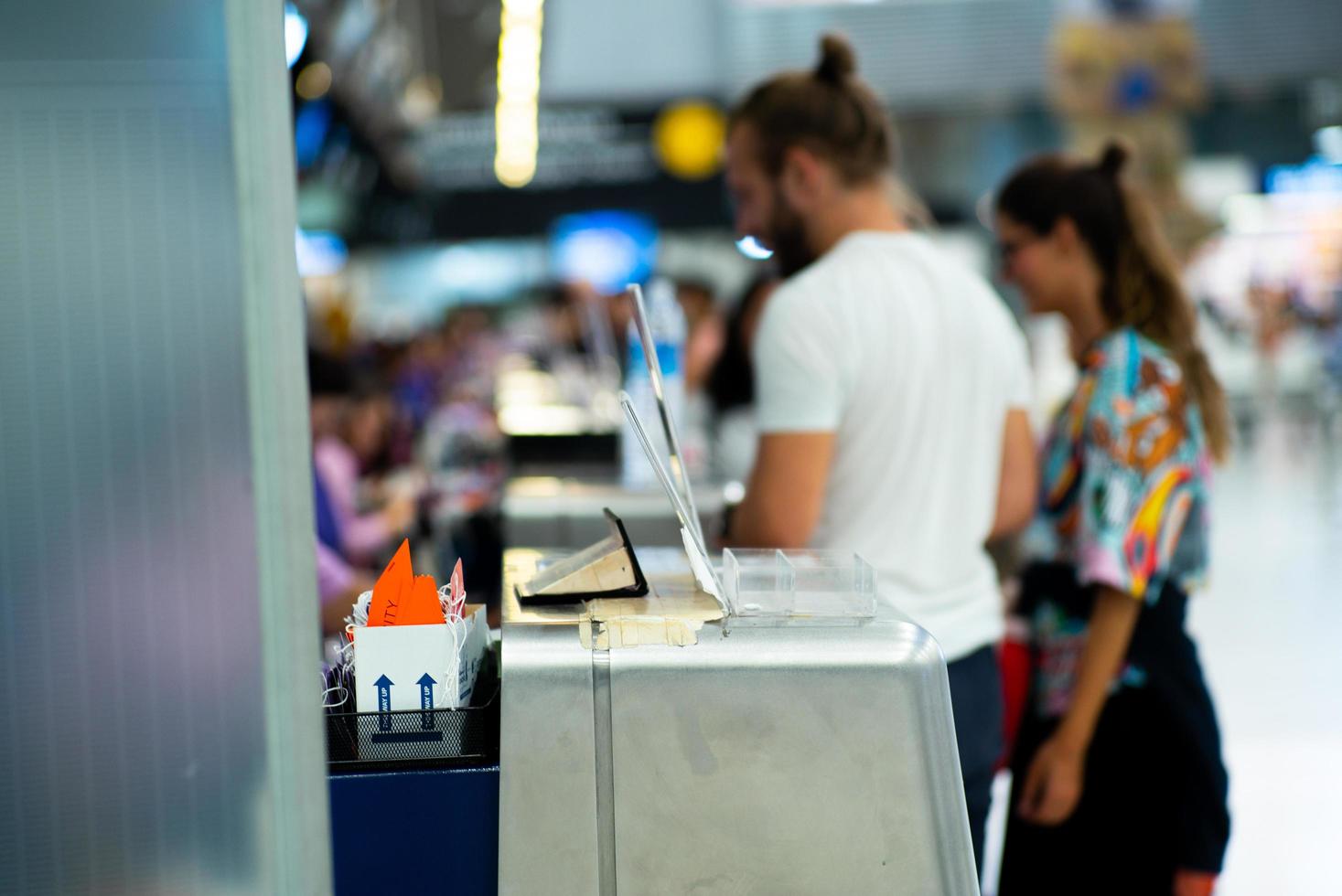 selectieve focus op metalen balie van luchtvaartmaatschappij op de luchthaven met onscherpe passagiers inchecken achtergrond. foto