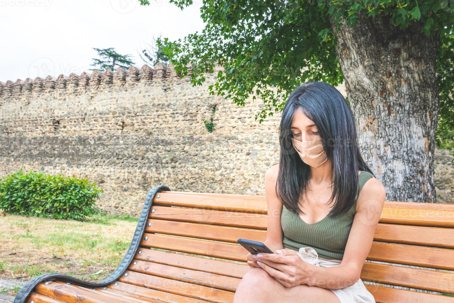 vrouw in een masker zittend op een bankje foto