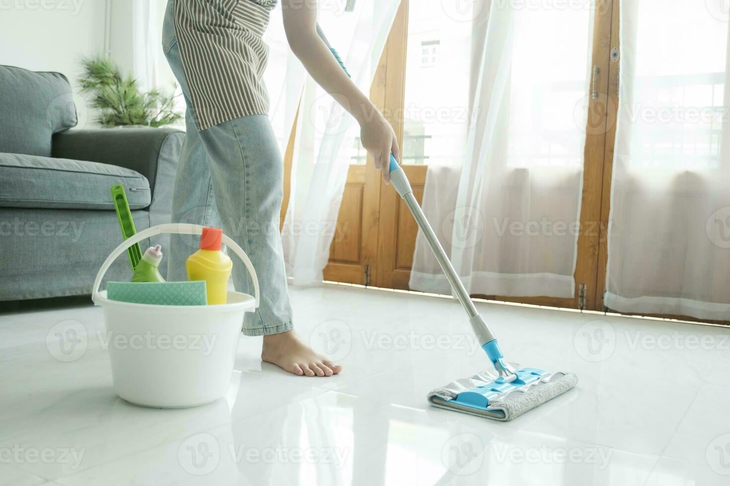 jong vrouw schoonmaak verdieping gebruik makend van dweilen Bij huis. foto