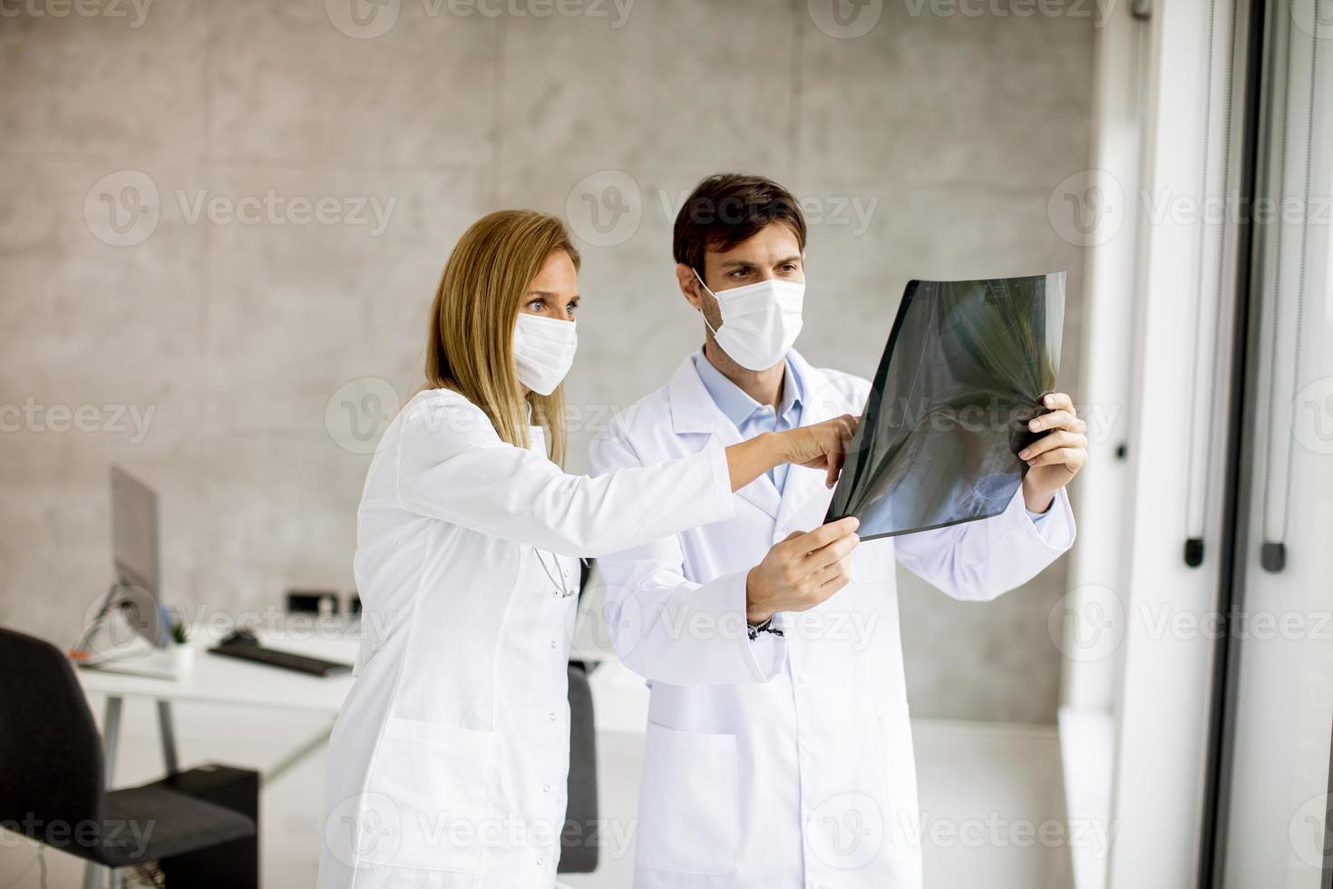 artsen in maskers kijken naar een röntgenfoto foto