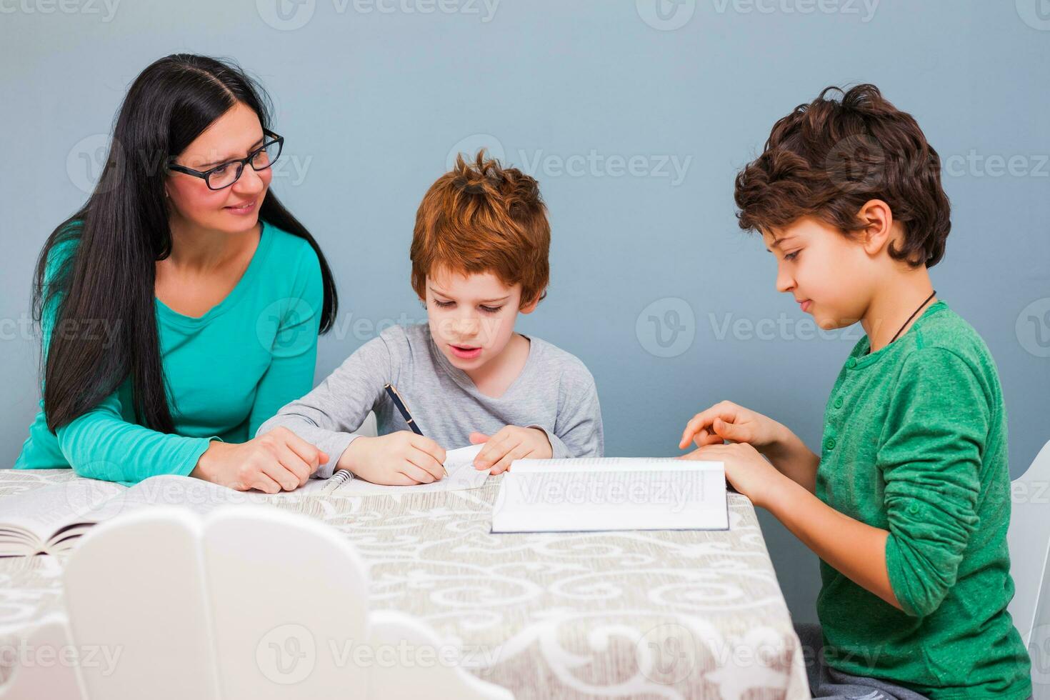 een moeder helpen haar kinderen met de huiswerk foto