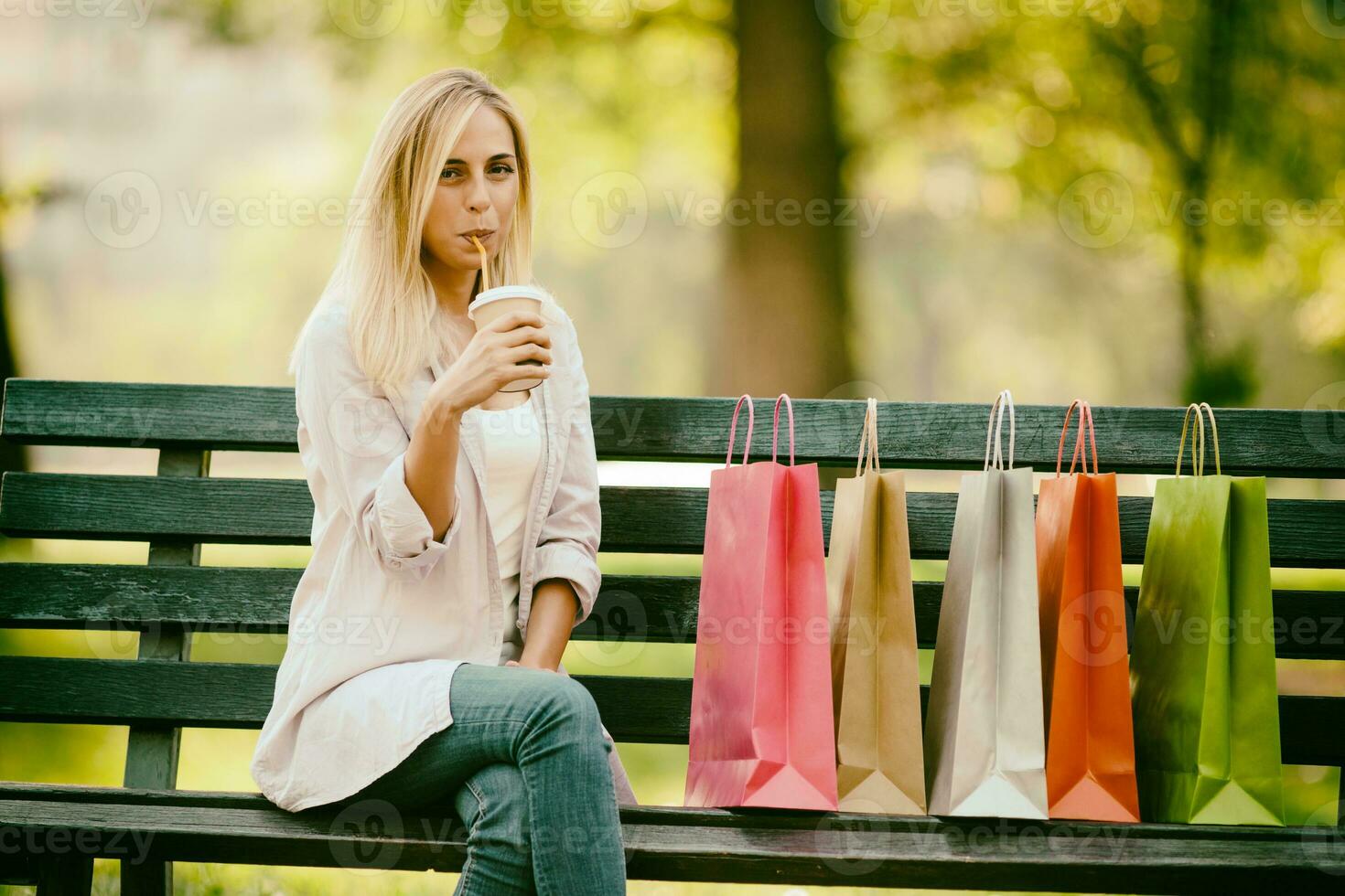 een vrouw resting in een park met boodschappen doen Tassen foto